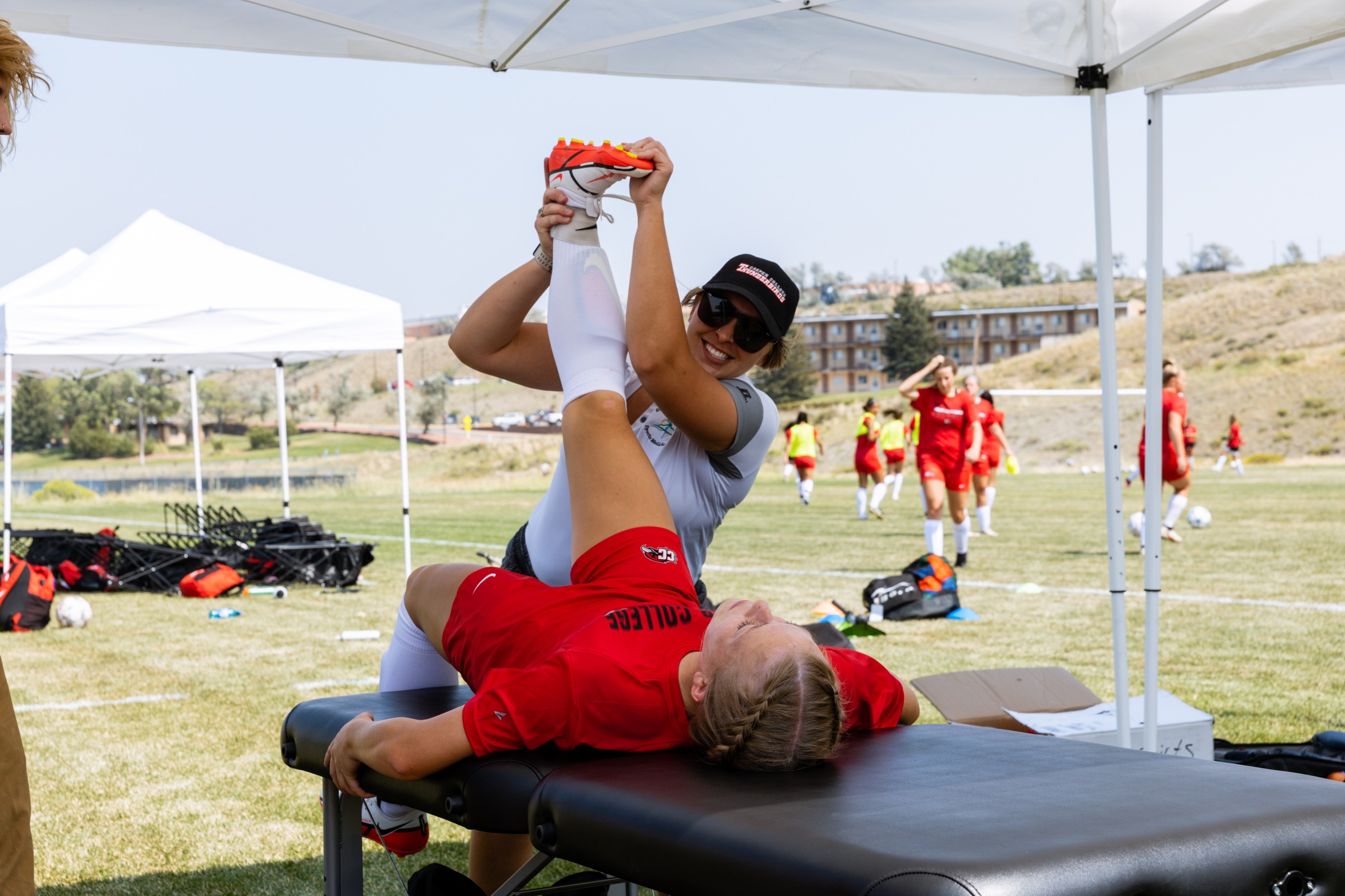 Athletic trainer at Casper College assisting an athlete in stretching before a match.
